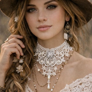May include: A woman wearing a brown hat with a cream-colored lace trim and a white lace choker necklace with a pearl pendant. She also wears layered necklaces and feather earrings. Her hair is styled with flowers.