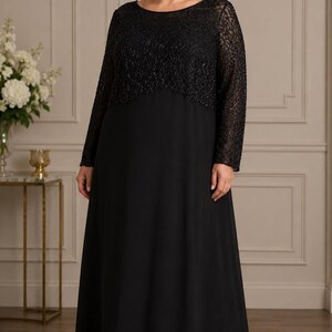 Puede incluir: Un vestido largo negro con corpi&ntilde;o con cuentas y mangas largas. El vestido tiene una falda fluida y un escote redondo. La mujer de la imagen lleva el vestido en una habitaci&oacute;n bien iluminada.
