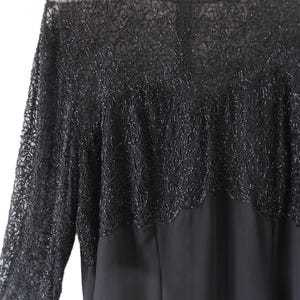 Puede incluir: Vestido negro con mangas largas. La parte superior del vestido presenta intrincados detalles de cuentas, creando un patr&oacute;n texturizado en forma de flor. Las mangas son transparentes y el vestido tiene un cuello redondo.