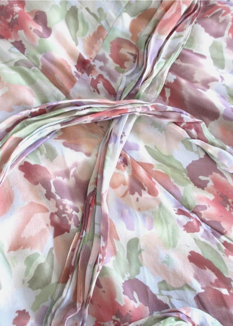 May include: A close-up of a floral patterned fabric in shades of pink, peach, and green. The fabric appears to be a lightweight material, possibly silk or a similar delicate weave. The design features a watercolor-like floral print.