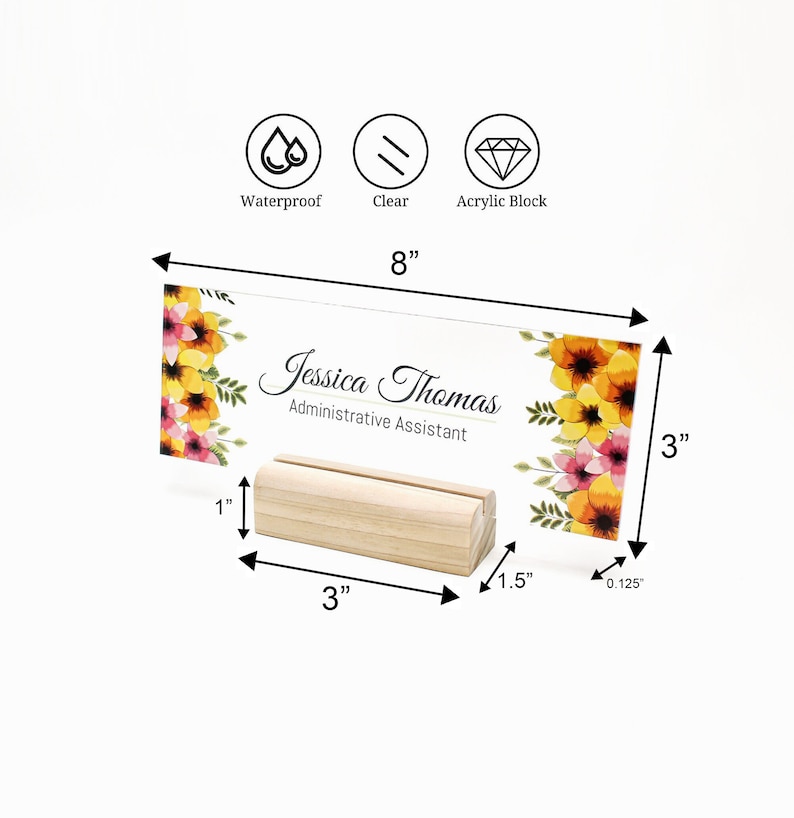 Puede incluir: Una placa de nombre de escritorio de acr&iacute;lico transparente con un dise&ntilde;o floral y el texto "Jessica Thomas, Asistente Administrativa". La placa mide 20,3 cm de ancho y 7,6 cm de alto. Se coloca sobre un soporte de madera de 7,6 cm de ancho.
