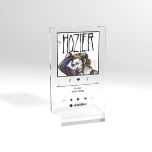 May include: A clear acrylic music player stand with a black and white image of a man on the front. The image is of the artist Hozier and the song title is "Work Song".
