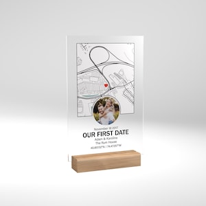 May include: A clear acrylic plaque with a black and white map, a red heart marking a location, and a photo of a couple. The text reads "November 18, 2017, Our First Date, Adam & Karolina, The Rum House, 40.85132°N / 74.47257°W".