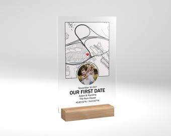May include: A clear acrylic plaque with a black and white map, a red heart marking a location, and a photo of a couple. The text reads "November 18, 2017, Our First Date, Adam & Karolina, The Rum House, 40.85132°N / 74.47257°W".