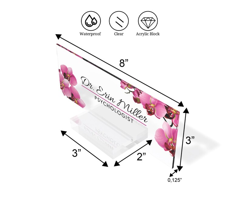 Może przedstawiać: Przezroczysty akrylowy stojak na biurko z r&oacute;żowym kwiatowym wzorem orchidei. Na stojaku widnieje napis "Dr. Erin Miller, Psycholog". Stojak ma 20,3 cm szerokości, 7,6 cm wysokości i 0,3 cm grubości.