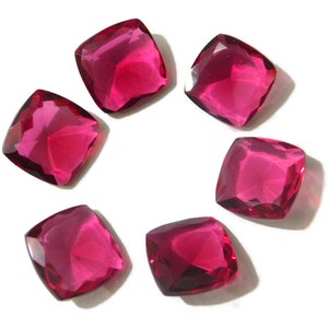 Puede incluir: Seis piedras preciosas de talla cojín de color rosa brillante, cada una con una forma cuadrada y un borde ligeramente redondeado. Las piedras preciosas están dispuestas en círculo sobre un fondo blanco.