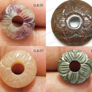 以下が含まれることがあります： 中央に穴が開いた、彫刻が施された4つの宝石ビーズ。ビーズは、ピンクと白、茶色、ピーチ、グレーなど、さまざまな色があります。各ビーズには、異なる彫刻が施された花柄または幾何学模様があります。ビーズにはD.B.05、D.B.06、D.B.07、D.B.08とラベルが付けられています。