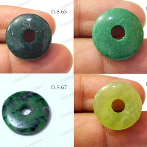 Può includere: Quattro perline di pietra preziosa di forma a ciambella di colore verde e giallo con fori al centro. Le perline sono etichettate D.B.65, D.B.66, D.B.67 e D.B.68.