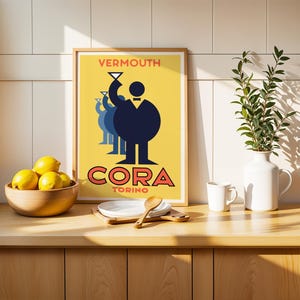 May include: A framed poster with the text "VERMOUTH CORA TORINO" features a stylized illustration of a figure raising a glass. The poster is on a wooden surface with a bowl of lemons, a white vase with greenery, and a small white mug.