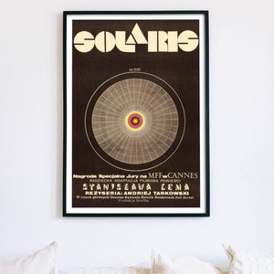 Könnte beinhalten: Ein gerahmtes Filmplakat für "Solaris" in einem schwarzen Rahmen. Das Plakat zeigt den Titel in einer markanten Schriftart und ein zentrales kreisförmiges Design. Text auf Polnisch ist unten sichtbar.