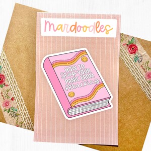 May include: Pink and orange sticker with a book illustration. The book cover says "How to Stop Your Panic From Attacking".