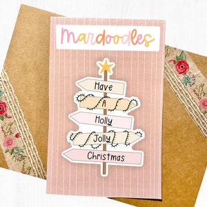 May include: A pink and white Christmas card with the text "mar doodles" at the top. The card features a Christmas tree made of signs with the words "Have a Holly Jolly Christmas" on them.