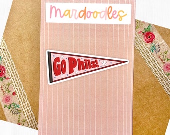 May include: A pink and white card with the text "mardoodles" in orange and yellow lettering. A white pennant sticker with the text "Go Phils!" in red lettering and a baseball graphic is on the card.