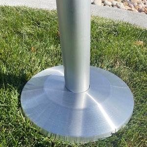May include: A silver metal base for a table or other furniture. The base has a round, flat top and a cylindrical stem.
