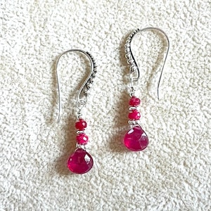 May include: A pair of silver dangle earrings with pink gemstone drops and silver beads.