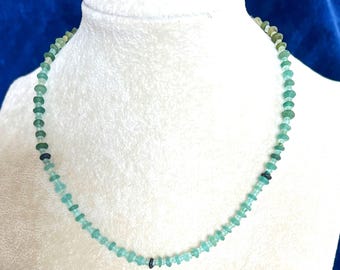 May include: A necklace made of light blue and green glass beads. The beads are small and round, and they are strung together on a thin cord.