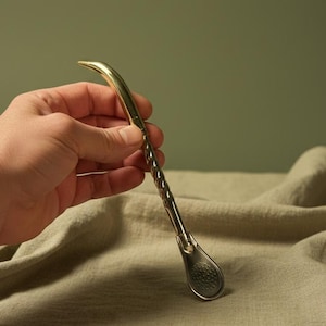 Peut inclure: Une bombilla à maté de couleur dorée avec une tige torsadée et un filtre en forme de cuillère. L'extrémité incurvée est lisse, tandis que l'extrémité du filtre comporte de petits trous. La bombilla est conçue pour boire du thé maté.