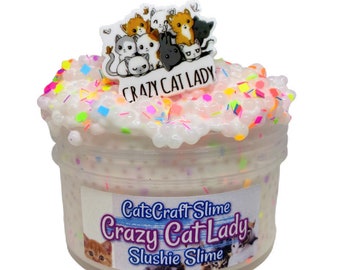 May include: A clear plastic container filled with white slime with colorful sprinkles and a white charm with a group of cartoon cats and the text "Crazy Cat Lady". The container has a label that reads "CatsCraft Slime Crazy Cat Lady Slushie Slime".