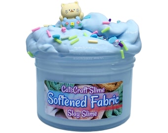 May include: A pot of pale blue slime decorated with sprinkles and a small cat figure. The pot has a label that reads "CatsCraft Slime Softened Fabric Slay Slime."