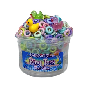 May include: A clear plastic container filled with clear slime, colorful ring-shaped beads, and small duck figurines. The container has a label that reads "CatsCraft Slime Ring Toss Clear Slime."