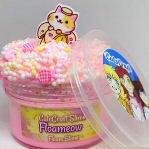 May include: Pink foam slime in a clear jar with a pink and yellow lid. The slime is topped with white and pink foam balls and colourful sprinkles. The jar has a label that says "CatsCraft Slime Floameow Foam Slime".