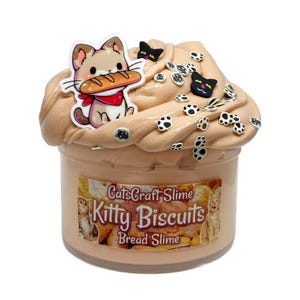 May include: A clear jar of light brown slime with a label that reads "CatsCraft Slime Kitty Biscuits Bread Slime". The slime is topped with black cat paw and cat face charms.