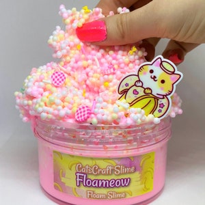 May include: Pink slime with white and yellow beads, a small cat charm with a banana and angel wings, and a label that reads "CatsCraft Slime Floameow Floam Slime".
