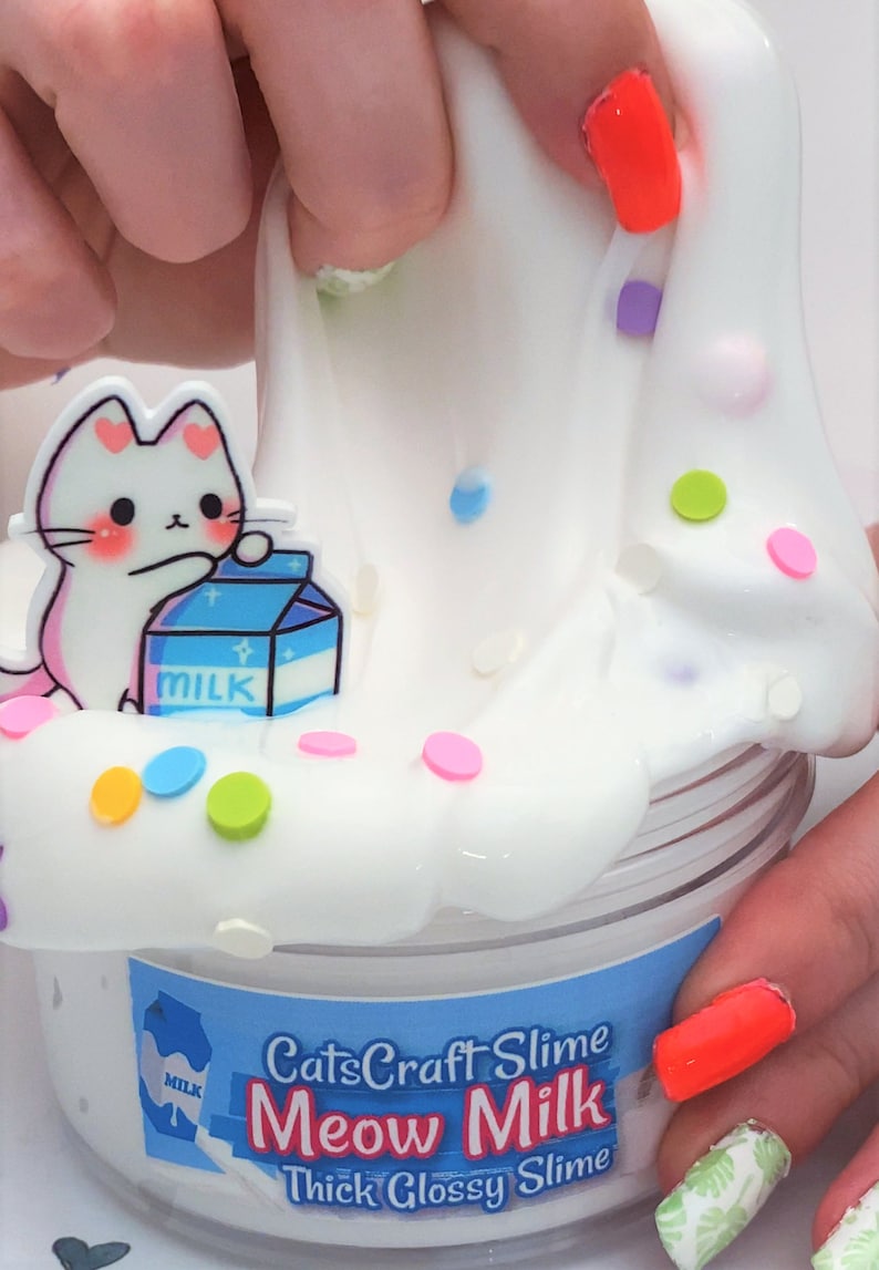 May include: White slime with colorful sprinkles and a cartoon cat holding a carton of milk. The slime is in a clear jar with a label that reads "CatsCraft Slime Meow Milk Thick Glossy Slime".