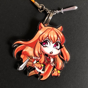 May include: A red-haired anime character with a sword keychain. The character is wearing a white and red dress and has a fox tail. The keychain has a silver charm and a yellow string.