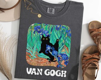 May include: A dark grey t-shirt with a black cat in a painting of blue irises. The text "VAN GOGH" is printed in white below the image.