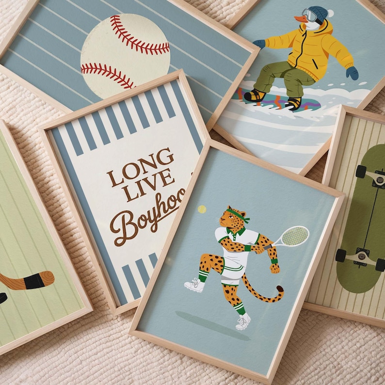 May include: A collection of framed art prints featuring sports and leisure themes. The prints include a baseball, a snowboarder, a tennis-playing leopard, a skateboard, and a hockey stick. The frames are light wood.