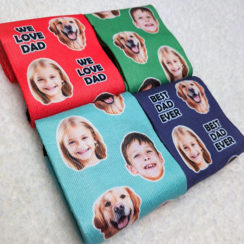 May include: Four pairs of colorful socks with a repeating pattern of faces and dogs. The socks have the text "We Love Dad" and "Best Dad Ever" printed on them.
