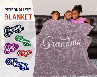 May include: A soft, pink personalized blanket with the word "Grandma" written in white cursive lettering. The blanket is covered in a repeating pattern of names, including "Joey", "Jenni", "Danielle", "Dylan", "Tyler", "Evangeline", "Noah", "Scarlett", "Fallyn", "Carissa", and "Brielle".