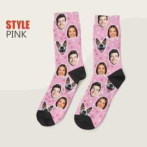 May include: A pair of pink socks with white polka dots. The socks feature a repeating pattern of faces and a dog's head.