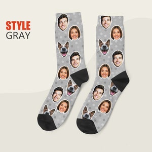 May include: A pair of gray socks with a white polka dot pattern. The socks feature multiple images of people and a dog's face.