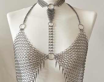 May include: A silver chainmail top with spikes hanging from the bottom. The top is worn on a white mannequin.