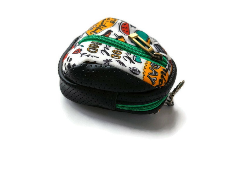 K&ouml;nnte beinhalten: Eine kleine, schwarze und wei&szlig;e Rei&szlig;verschlusstasche mit einem gr&uuml;nen Rei&szlig;verschluss. Die Tasche hat ein schwarz-wei&szlig;es Punkte-Muster und den Text "Good Day" auf der Vorderseite.