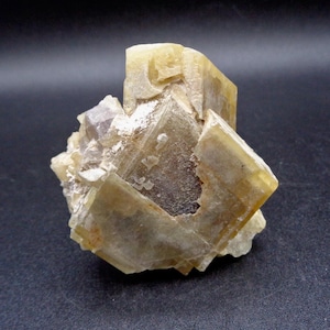 May include: A close-up of a natural mineral specimen. The crystal formation has a complex, geometric structure with a pale yellow and tan colour. The mineral has a rough, textured surface with some translucent areas.