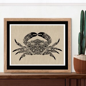 May include: A black and white illustration of a crab made up of floral patterns. The crab is framed in a brown wood frame and is displayed on a wooden shelf.