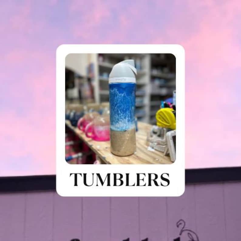May include: A blue and white tumbler with a wave design. The tumbler is sitting on a wooden table with other tumblers in the background. The text "TUMBLERS" is printed below the image.