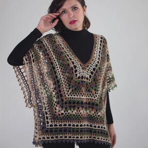 May include: A crocheted poncho with a V-neck and a geometric pattern in shades of brown, green, and beige.