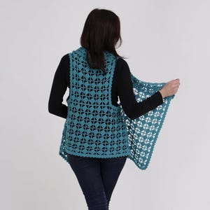 May include: A teal crochet vest with a lacy pattern. The vest has a wide, open neckline and a longer back than front.