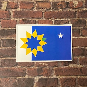 May include: A sticker featuring a blue and white flag with a yellow stylized sunflower and a white star in the upper right corner.