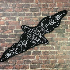 May include: Black felt patch with a white embroidered design of a solar system with planets and stars.