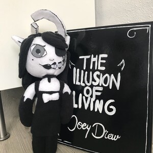 May include: Black and white plush toy of a character with a black dress and horns. The toy is standing next to a black sign with white text that reads "The Illusion of Living Joey Drew".