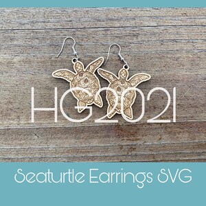 May include: A pair of wooden sea turtle earrings with intricate floral designs. The earrings are brown and have silver hooks.