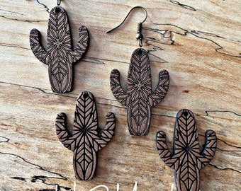 Könnte beinhalten: Ein Set aus drei Holz-Kaktus-Ohrringen mit geometrischem Muster. Die Ohrringe sind braun mit schwarzen Details und haben ein einfaches Haken-Design.