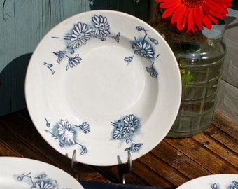 May include: A set of six white ceramic soup bowls with a blue floral pattern. The bowls are stacked on top of each other.
