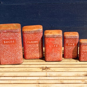 May include: Set of five red speckled metal canisters with white lettering. The canisters are labeled "SUCRE", "FARINE", "CAFÉ", "THÉ", and "POIVRE".