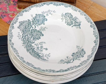 May include: A stack of vintage white ceramic soup bowls with a green floral design. The bowls have a scalloped edge and a delicate floral pattern.
